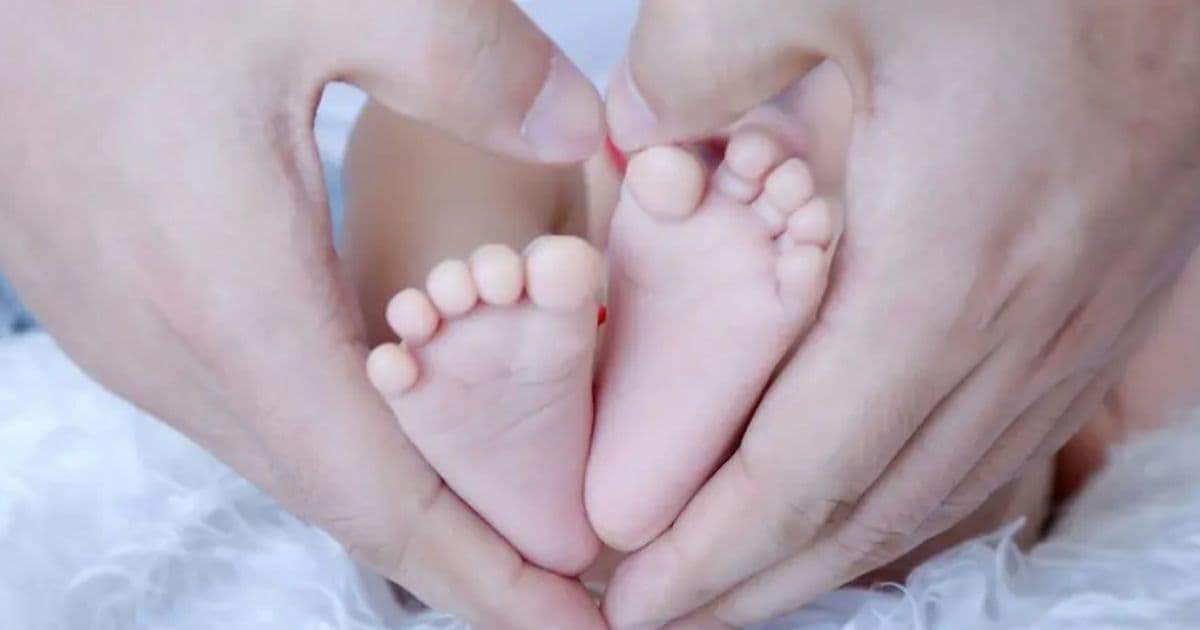Close-up image of a newborn baby’s feet held gently in adult hands for a perinatal loss and bereavement support workshop